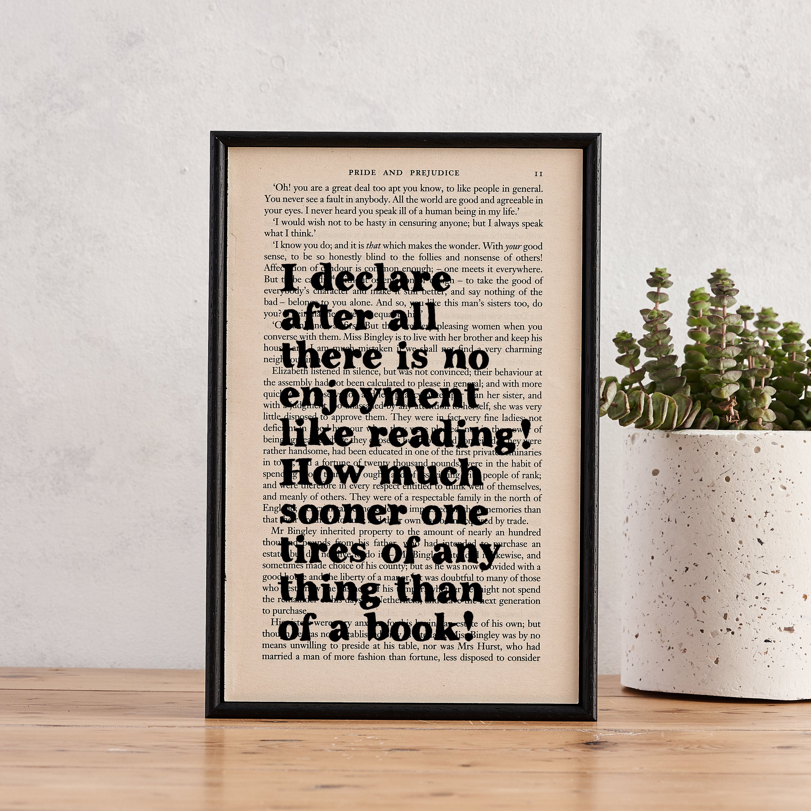 Framed book page print with the quote “I declare after all there is no enjoyment like reading” from Pride and Prejudice, styled with a succulent plant.