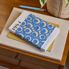 Book with a blue and white cover on a wooden surface with a plant in the background