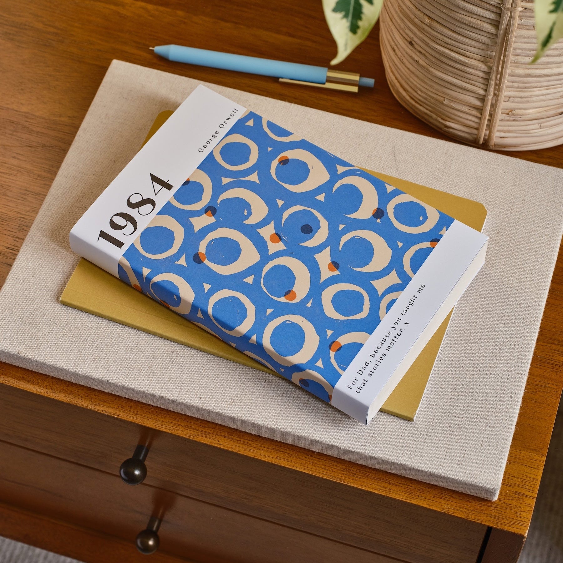 Book with a blue and white cover on a wooden surface with a plant in the background