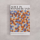 Bookishly edition of Alice in Wonderland by Lewis Carroll with a blue and rust dot-patterned dust jacket and personalised message printed on the front cover.