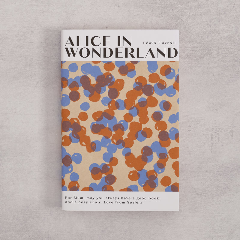 Bookishly edition of Alice in Wonderland by Lewis Carroll with a blue and rust dot-patterned dust jacket and personalised message printed on the front cover.