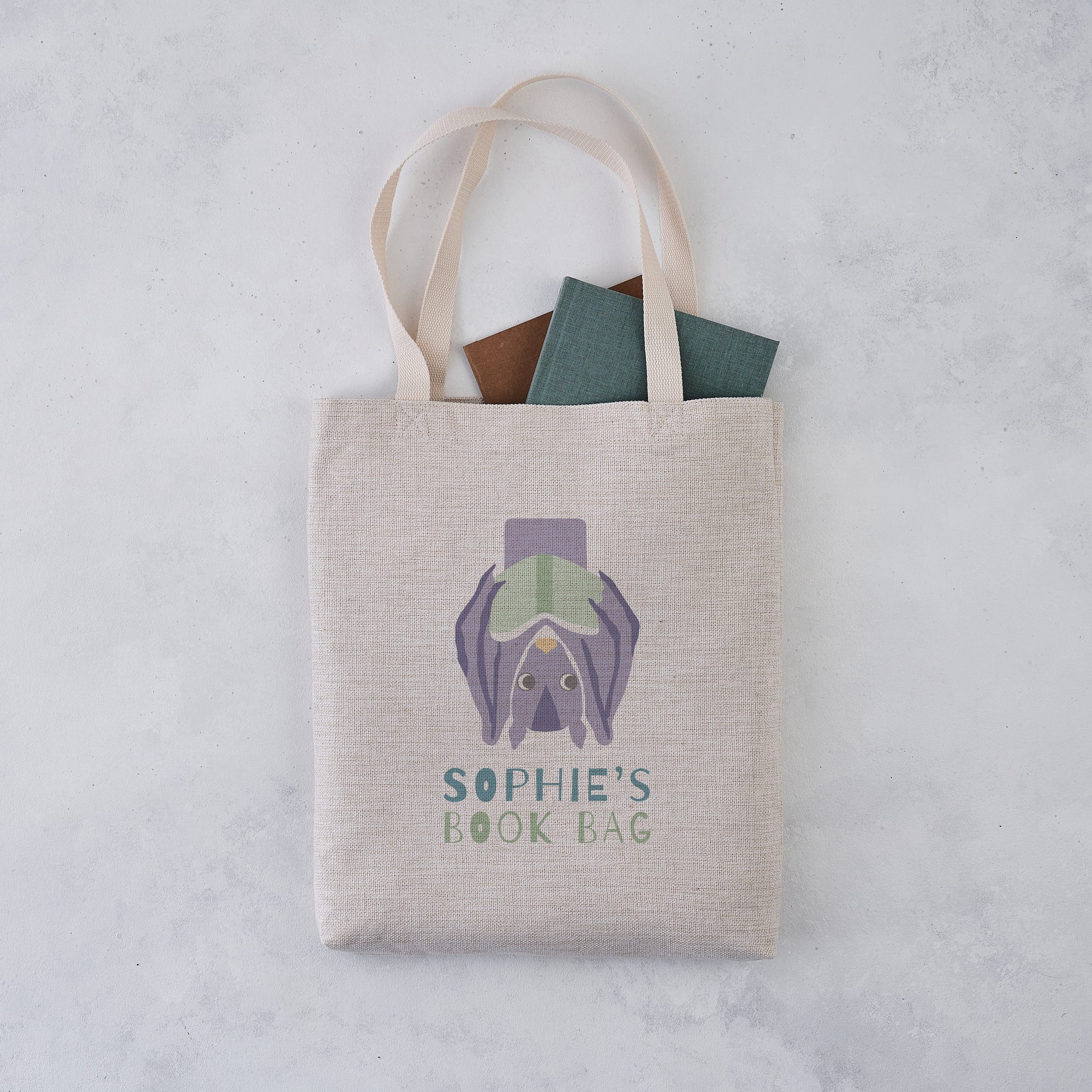 Personalised book bag tote with an upside down bat holding a book and the text “Sophie’s Book Bag” printed above.