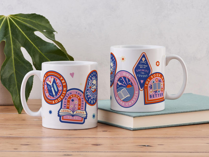 A white mug with bookish sticker designs printed onto it