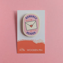 Romance Reader wooden pin on a pink background, featuring a love letter and arrows on a pink badge design.