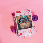 Wrapped book advent calendar with Emily Brontë edition partly unwrapped, surrounded by pink and purple baubles on a pink background.