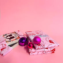 Partly unwrapped books from the Bookishly book advent calendar, showing custom dust jackets with pink and purple baubles on a pink background.
