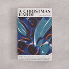 Bookishly edition of A Christmas Carol by Charles Dickens with a blue and rust abstract dust jacket and personalised message printed on the front cover.