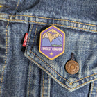 Fantasy Reader wooden pin attached to the pocket of a denim jacket.