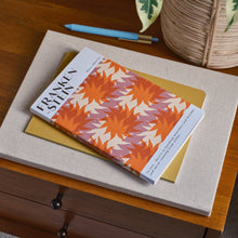 Book titled 'Frankenstein' with a colorful cover on a wooden surface next to a plant.