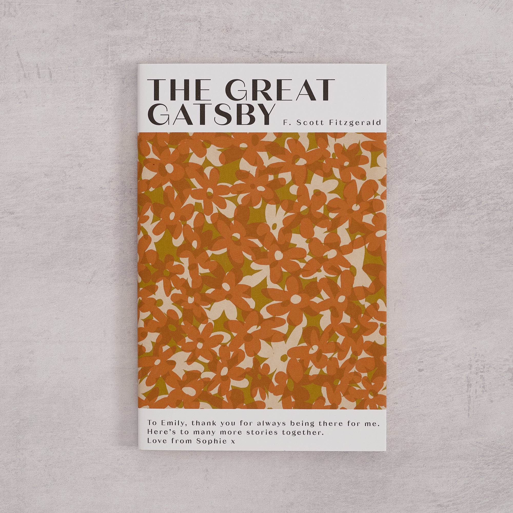 Bookishly edition of The Great Gatsby by F. Scott Fitzgerald with an orange daisy-patterned dust jacket and personalised message printed on the front cover.
