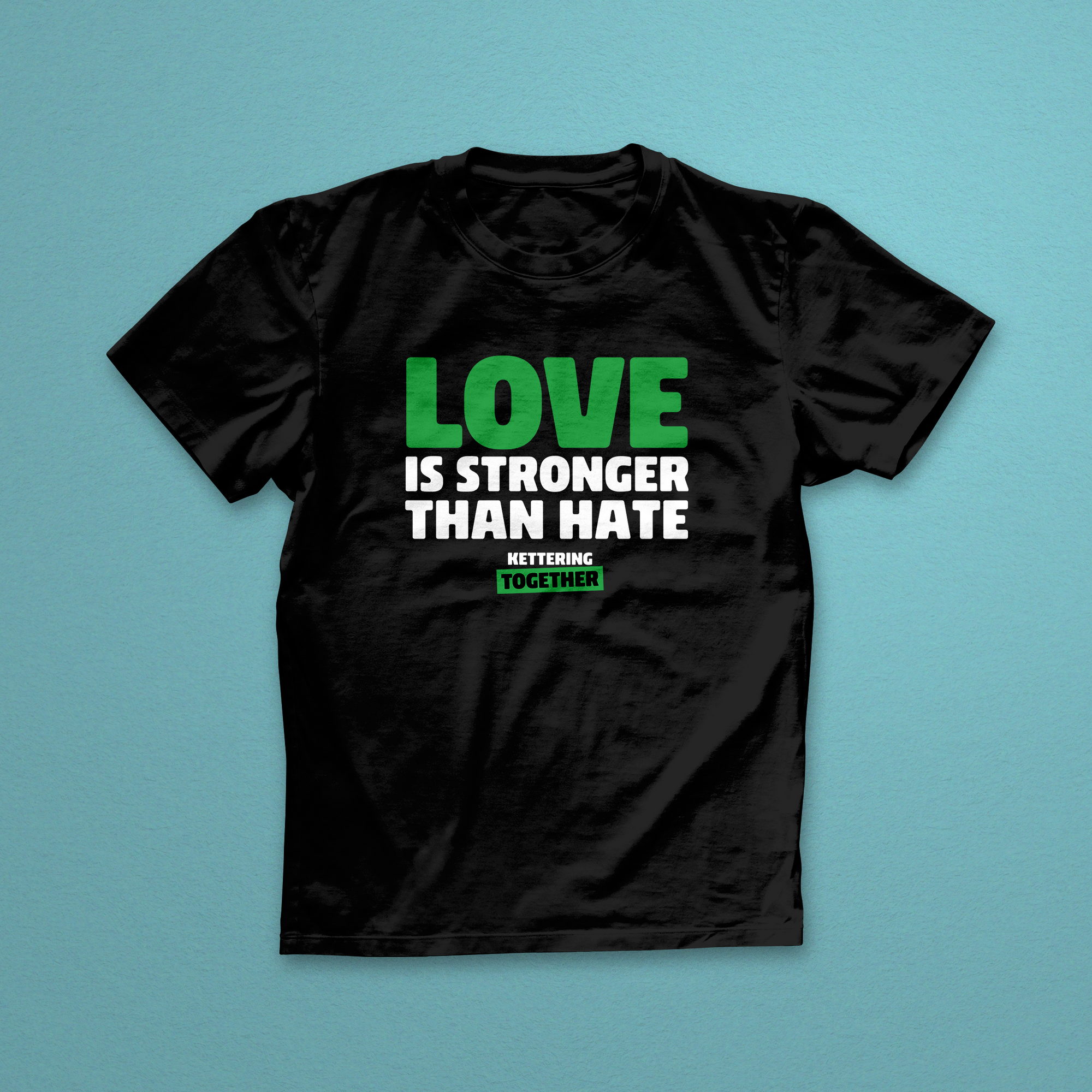 Black t-shirt with 'Love is Stronger Than Hate' text on a teal background