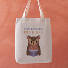 Personalised book bag tote with an owl reading a blue book and the text “Miss Hassan’s Book Bag” printed above.