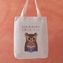 Personalised book bag tote with an owl reading a blue book and the text “Miss Hassan’s Book Bag” printed above.