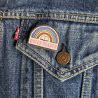 Queer Reader wooden pin attached to the pocket of a denim jacket.