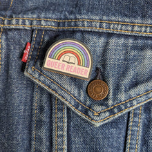 Queer Reader wooden pin attached to the pocket of a denim jacket.