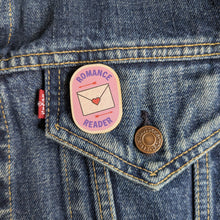 Romance Reader wooden pin attached to the pocket of a denim jacket.