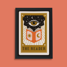 Framed art print with tarot card design showing an eye above an open book with sun and moon symbols, titled “The Reader.”