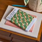 Two books on a wooden surface with a plant in the background