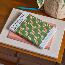Two books on a wooden surface with a plant in the background