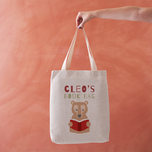 Tote bag with bear design and 'Cleo's Book Bag' text on a peach background
