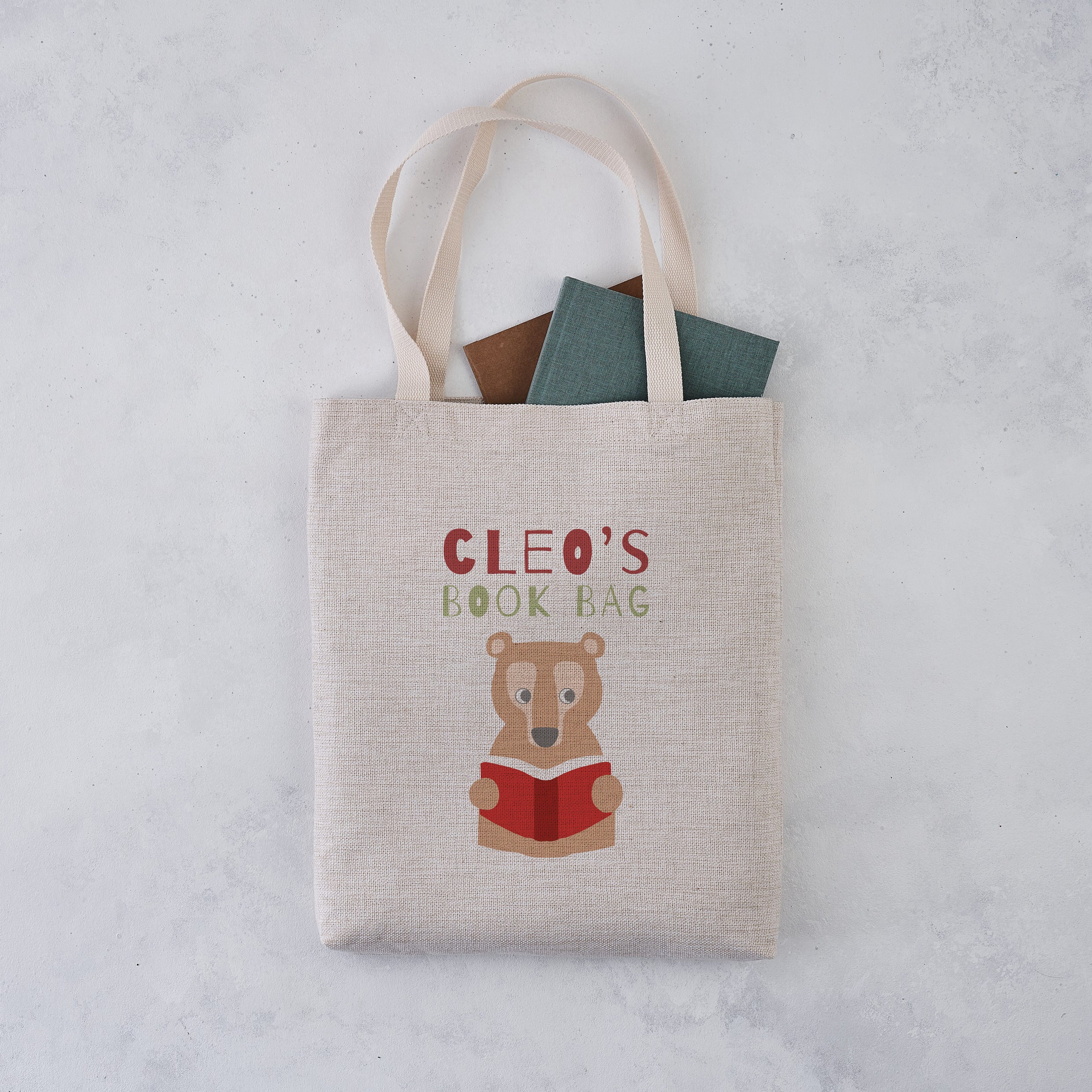 Personalised book bag tote with a bear reading a red book and the name “Cleo’s Book Bag” printed above.