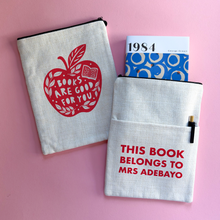 Personalised book sleeve featuring “Books Are Good for You” red apple design on one side and “This Book Belongs To Mrs Adebayo” on the other, styled on a pink background with a copy of 1984 by George Orwell.
