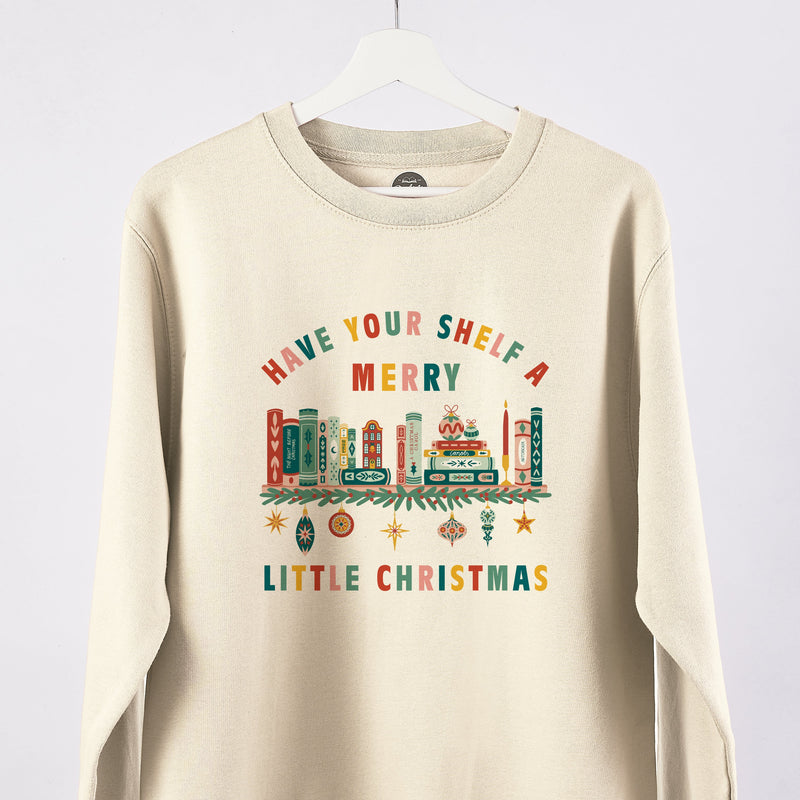 A cream sweatshirt with a Christmas bookshelf design and the wording 'Have your shelf a merry little Christmas.'