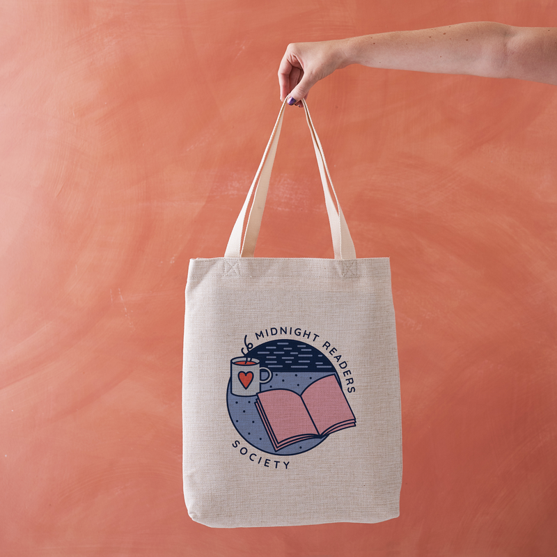 Natural-coloured tote bag with “Midnight Readers Society” design featuring an open book, night sky, and steaming mug illustration.