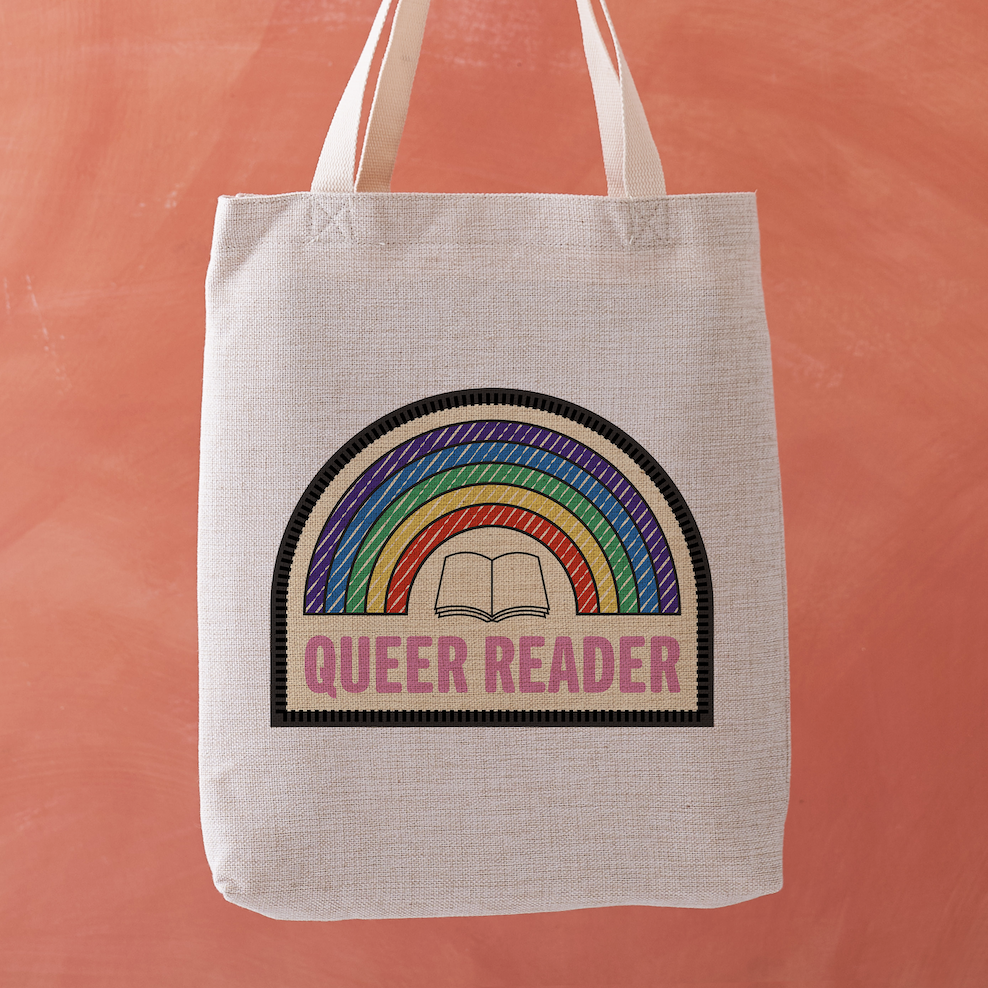 Queer Reader tote bag with a stitched badge-style design featuring a rainbow and open book on a soft yellow background.
