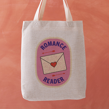 Romance Reader tote bag featuring a stitched badge-style design with a love letter and arrows on a soft pink background.
